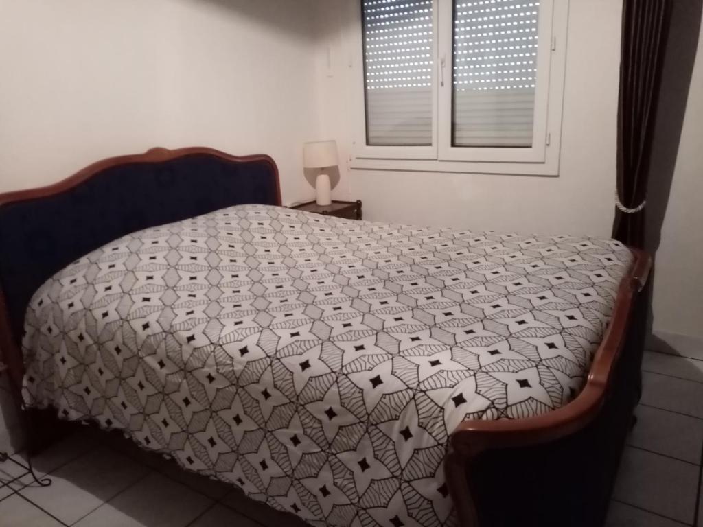 ein Schlafzimmer mit einem Bett mit einer Decke darauf in der Unterkunft chambre meublée in Champigneulles