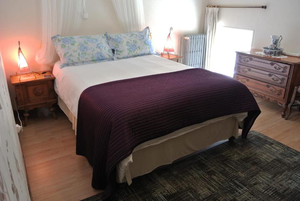 a bedroom with a large bed with a purple blanket at La Bannerie in Mesnil-Clinchamps