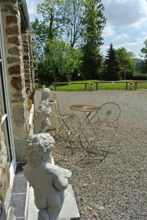 a statue of aouple of chairs and a table at La Bannerie in Mesnil-Clinchamps