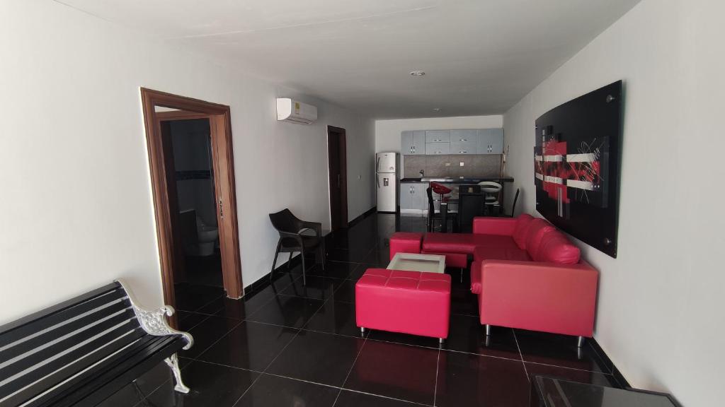 sala de estar con sofá rojo y sillas rosas en Cabaña 5 Castillo Club House, en Coveñas