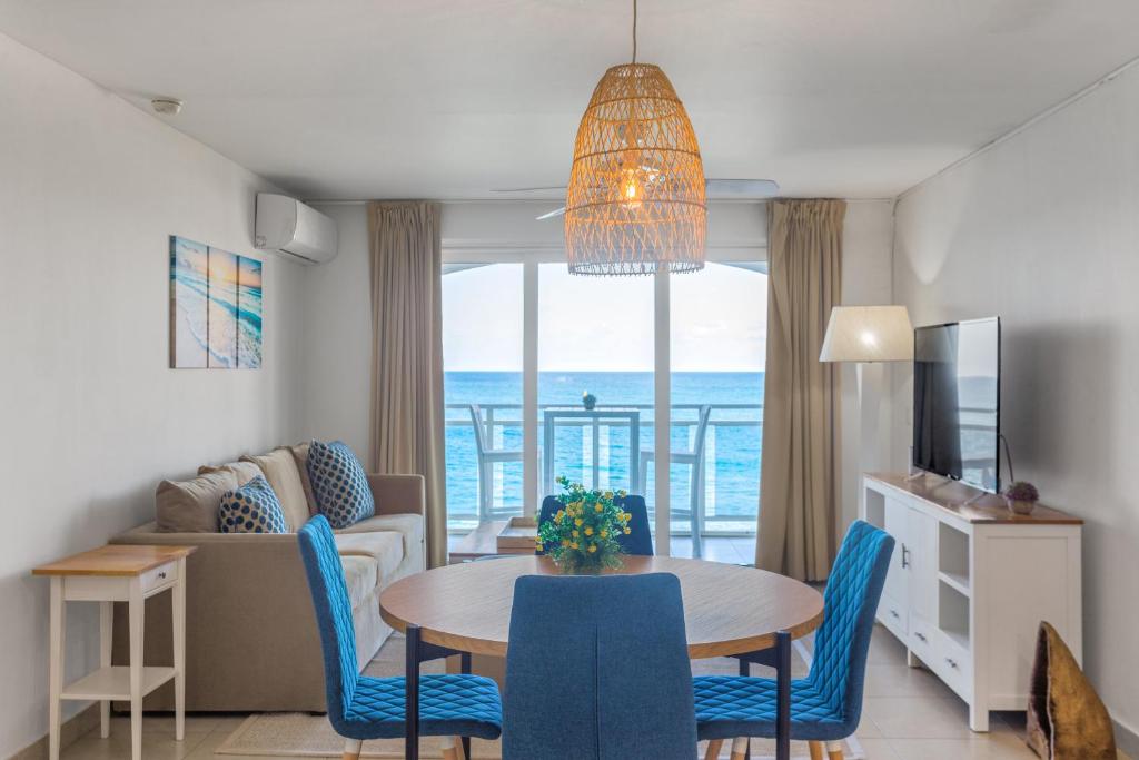 uma sala de estar com uma mesa e cadeiras e um sofá em Sunset Beach Condo - Luxury 1BR Suite next to The Morgan Resort em Maho Reef