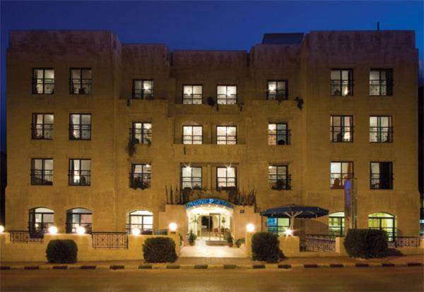 a large brick building with a front entrance at night at Delmon Suites in Amman