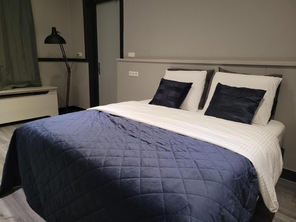 a large bed with blue and white sheets and pillows at Lakeside Studio near Amsterdam in Warder
