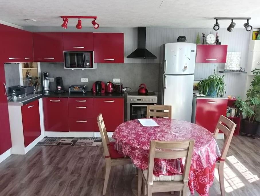 a kitchen with red cabinets and a table with chairs at Les Aigus in Saint-Pierre