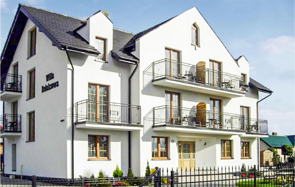 Biały dom z balkonem i ogrodzeniem w obiekcie Beautiful Apartment In Karwia With Outdoor Swimming Pool w Karwii