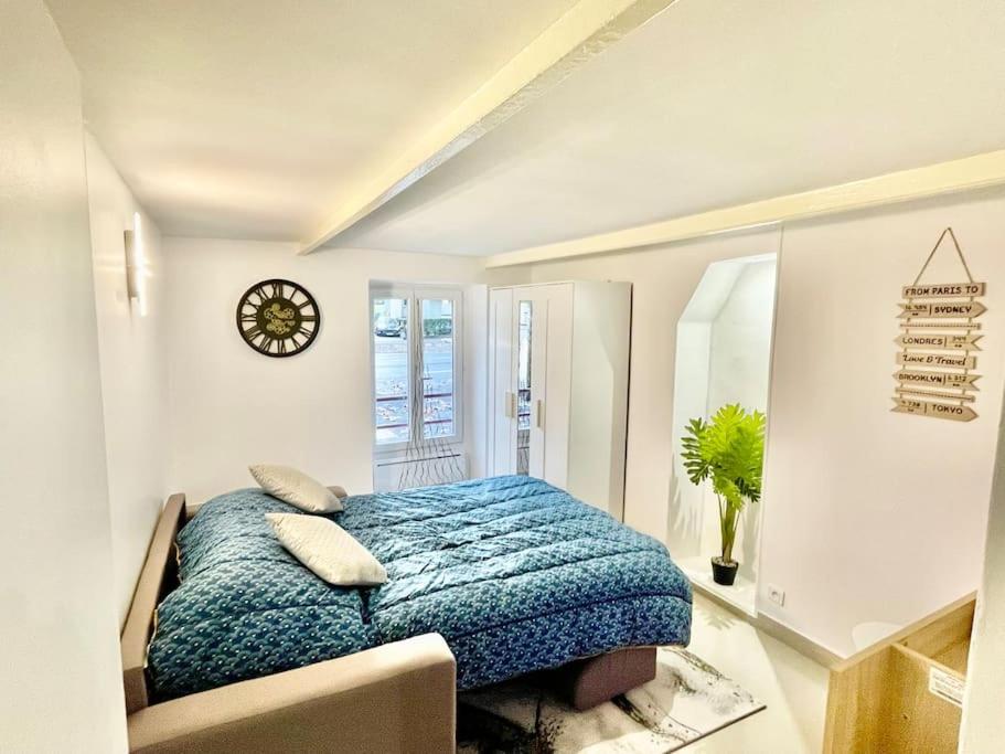 ein Schlafzimmer mit einem Bett und einer Uhr an der Wand in der Unterkunft Entre Paris, Versailles et La Défense in Chaville