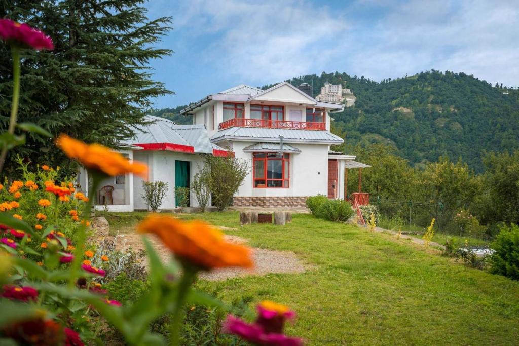 a house in a yard with flowers in front of it at StayVista at Sunshine Estate 2BR with Outdoor Sitting in Chail