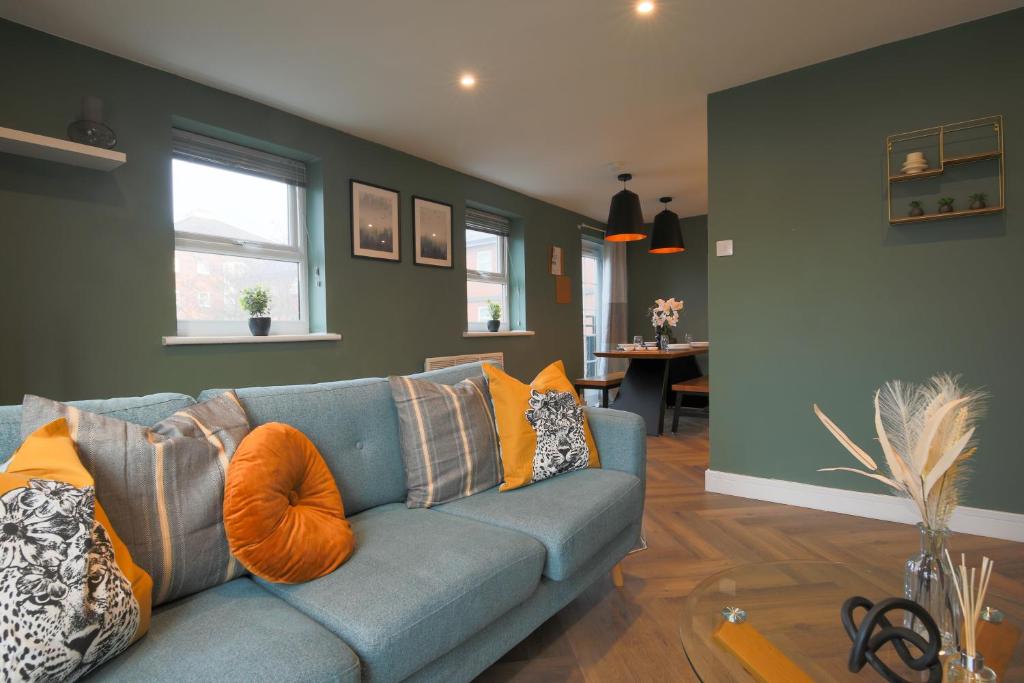 ein Wohnzimmer mit einem blauen Sofa und orangefarbenen Kissen in der Unterkunft Stayright Stylish Cardiff Bay 2 Bed Apartment- Private Parking & 10 mins to Bay & City in Cardiff