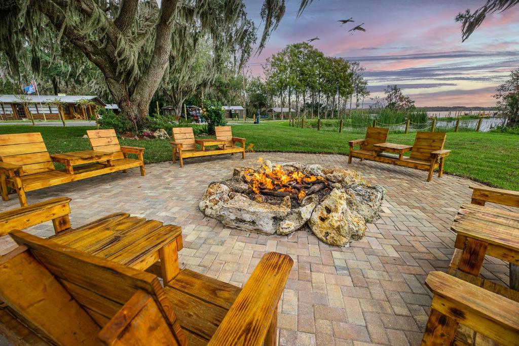 a fire pit with benches and a bunch of logs at Idlewild Lodge and RV Park in Lake Panasoffkee