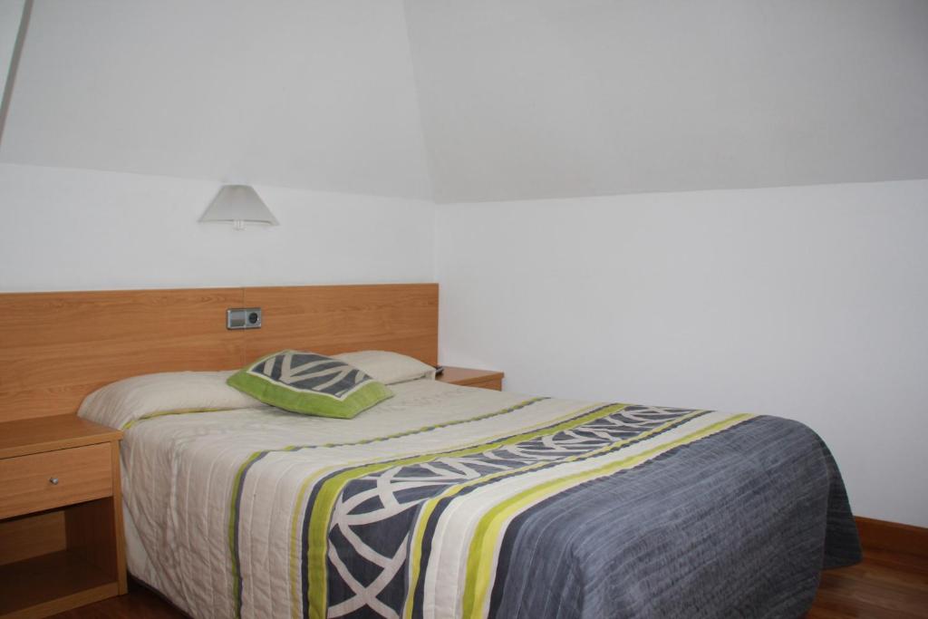 1 dormitorio con 1 cama con cabecero de madera en Pension Txiki, en Isaba