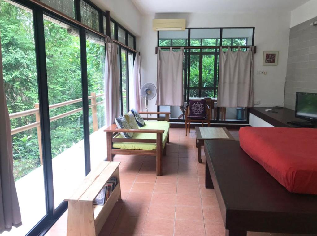 a living room with a bed and a couch and windows at Gaze Studio: Modern Spacious Jungle Stay in Pantai Cenang