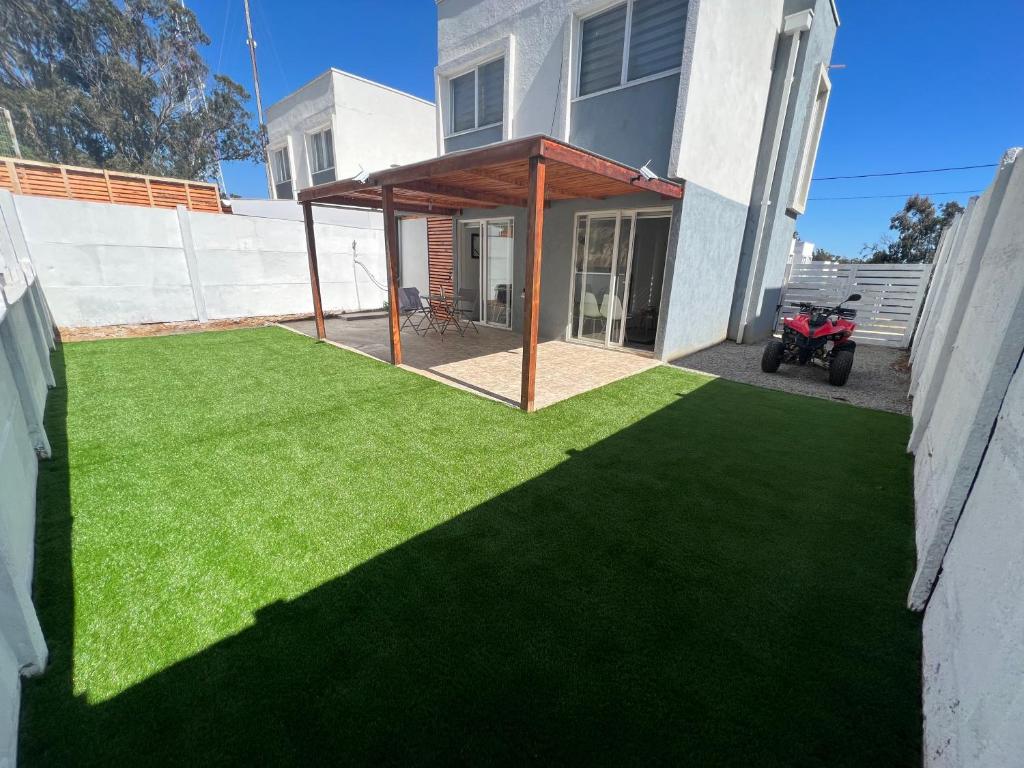 um pátio com relva verde em frente a uma casa em Casa Playa el Tabo en Condominio Estilo Mediterraneo em El Tabo
