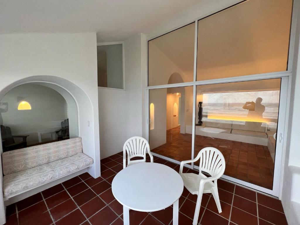 a white table and chairs in a room with a window at OceanBlue Resort in Christ Church
