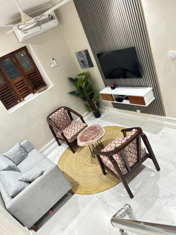 a living room with a couch and chairs and a tv at Najma's villa in Stone Town