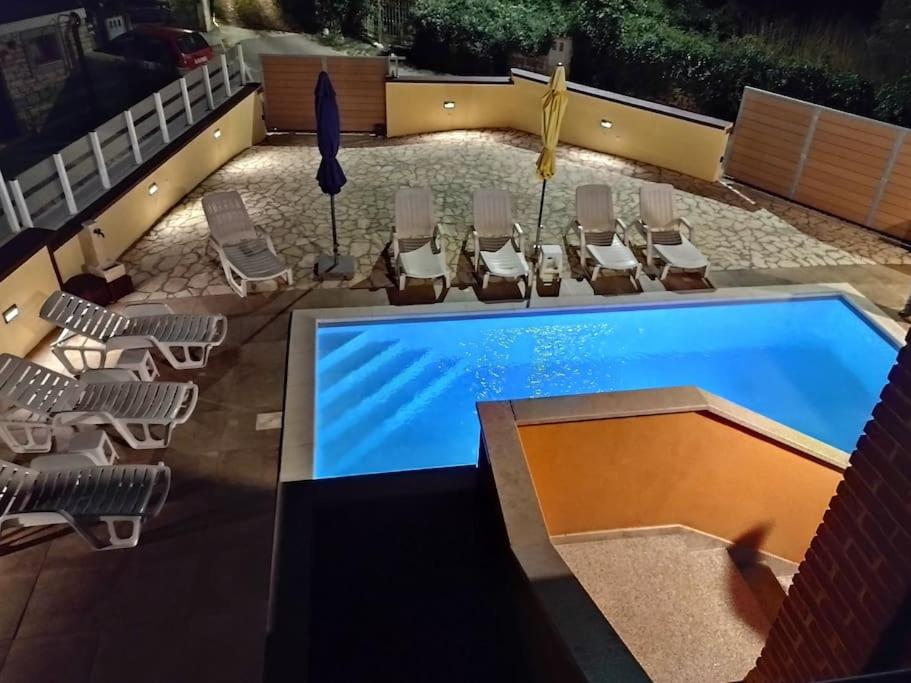 a pool with chaise lounge chairs and a group at Casa Bozzero in Krnica
