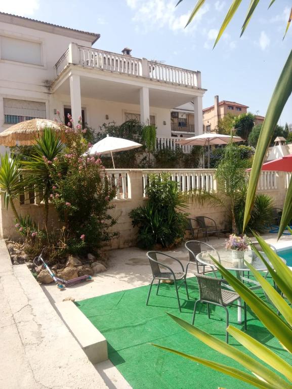 een huis met stoelen en een groen tapijt naast een zwembad bij Chalet Urbanización Alcolea in Córdoba
