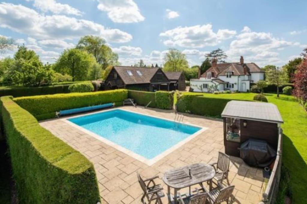 a swimming pool in the middle of a yard at 6 Bed Countryside Mansion With Tennis Court & Swimming Pool with Parking in East Horsley