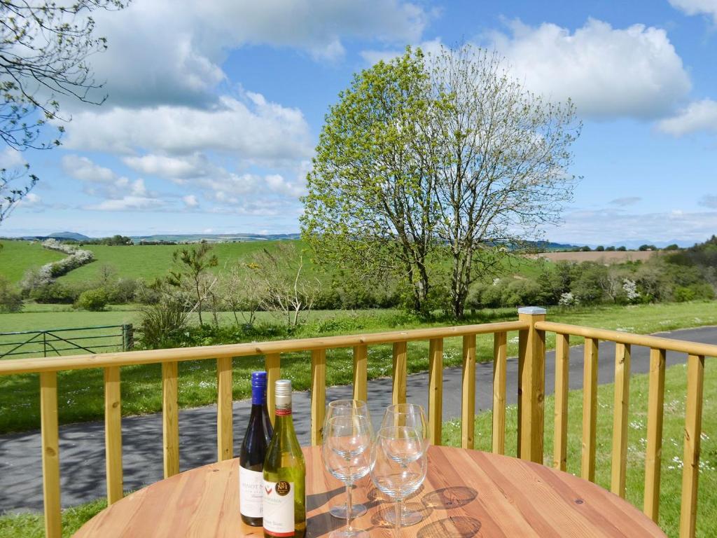 a wooden table with wine bottles and glasses on a balcony at Yonderton Mcgill Cottage - Uk11182 in Hollybush