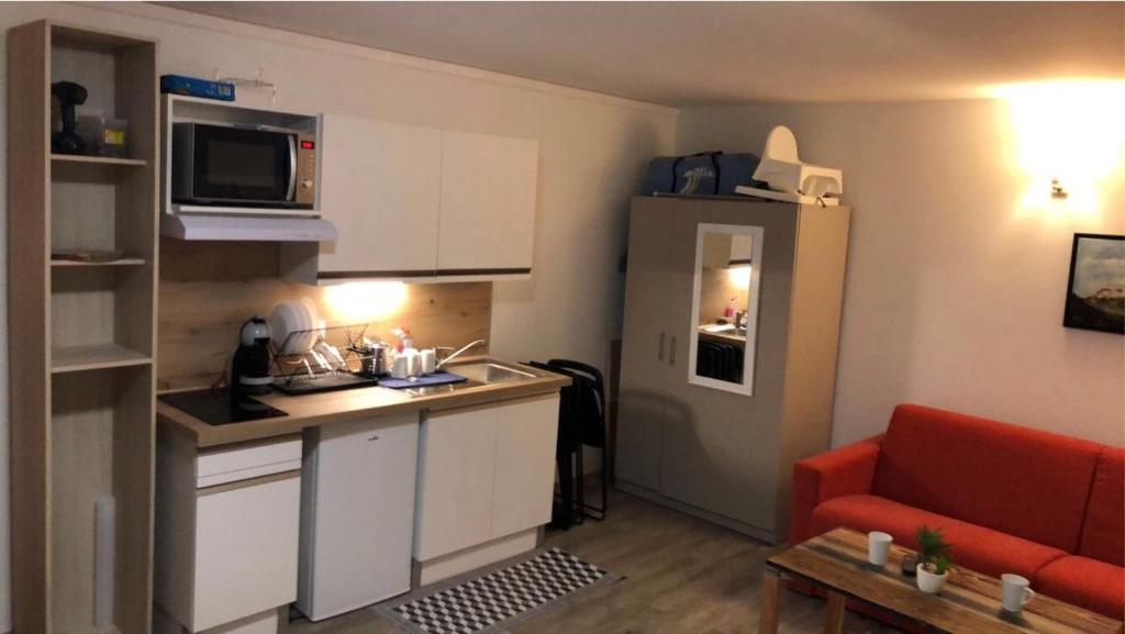 a small kitchen with a red couch in a small apartment at Au bout du bois Piscine sauna hammam accessible en saison et le logement accessible toute l annee in Les Déserts