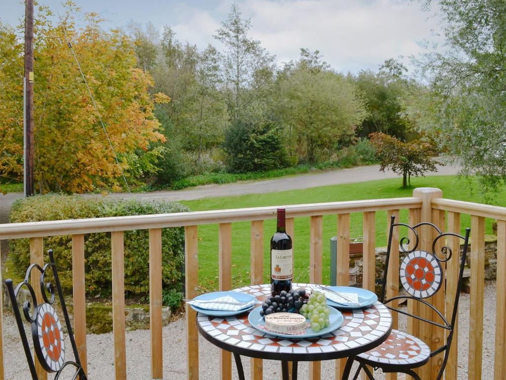 a table with a bottle of wine on a balcony at Barn Owl Bothy in Westward