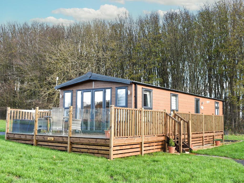 a tiny house with a large deck in a field at Doodles At Brid in Sewerby