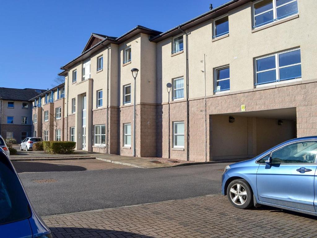 Niebieski samochód zaparkowany przed budynkiem w obiekcie Ness-side Apartment w mieście Inverness