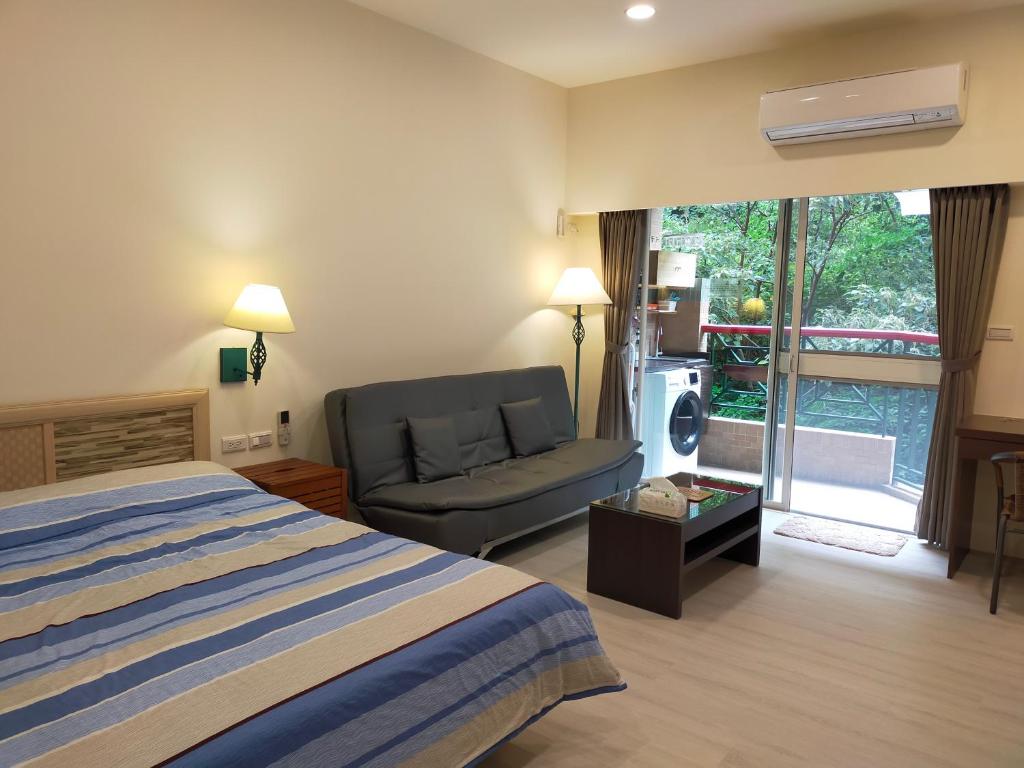une chambre d'hôtel avec un lit, un canapé et une fenêtre dans l'établissement 知本溫泉家, à Hua-yüan