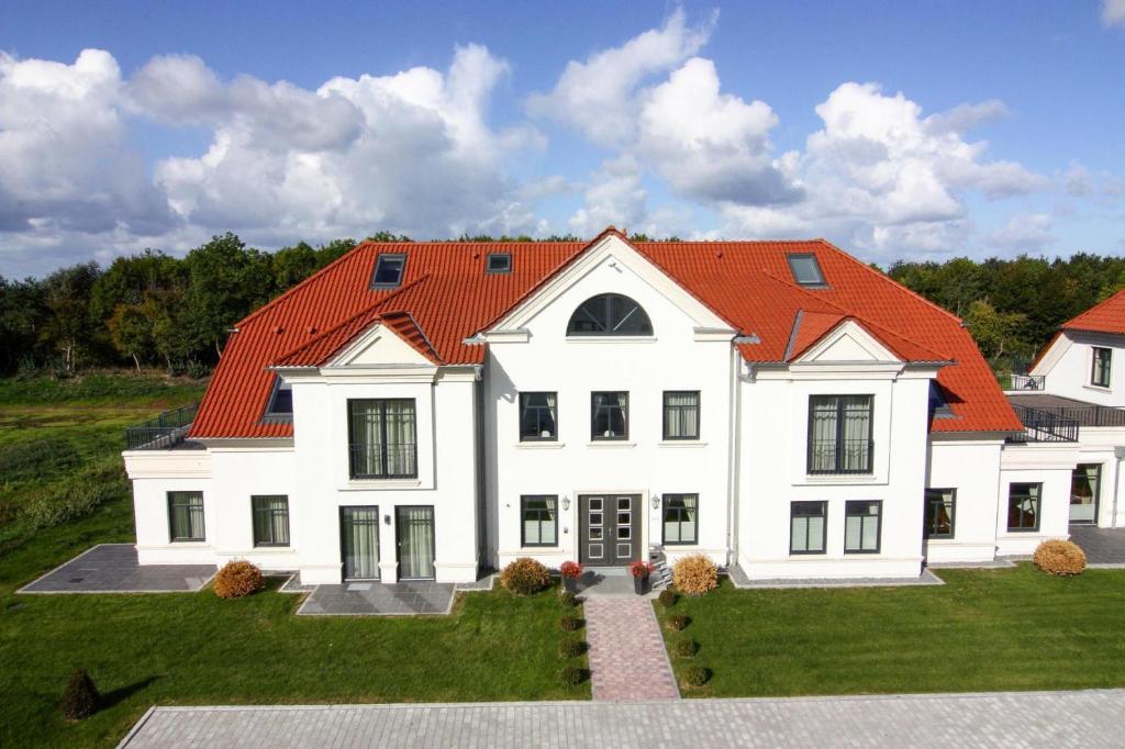 a large white house with an orange roof at Appartements im Avalon Hotel Bellevue, Fehmarn in Fehmarn