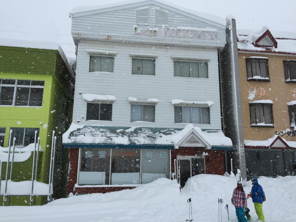 due persone in piedi nella neve di fronte a un edificio di Koizumiya - Vacation STAY 14238v a Yuzawa