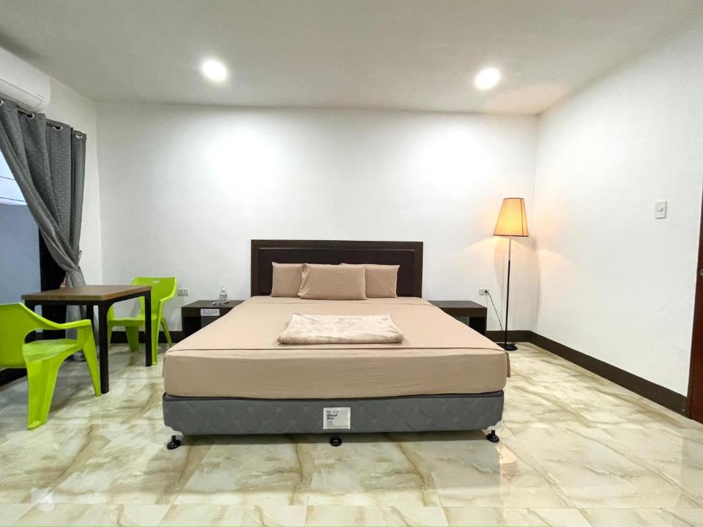 a bedroom with a bed and a table and green chairs at MGH Alona Resort in Panglao Island