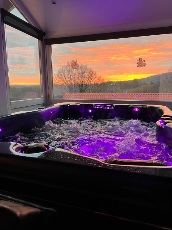 a jacuzzi tub with purple water and a sunset at Deluxe Apartments Franjkovic in Seliste Dreznicko