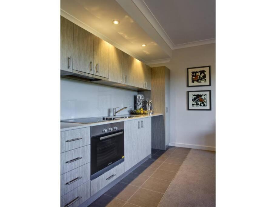 a kitchen with white cabinets and a stove top oven at Bright 1 Bedroom Joondalup Stay in Perth