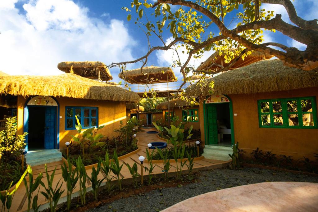 dom z dachem krytym strzechą i patio w obiekcie One At Goa w mieście Canacona