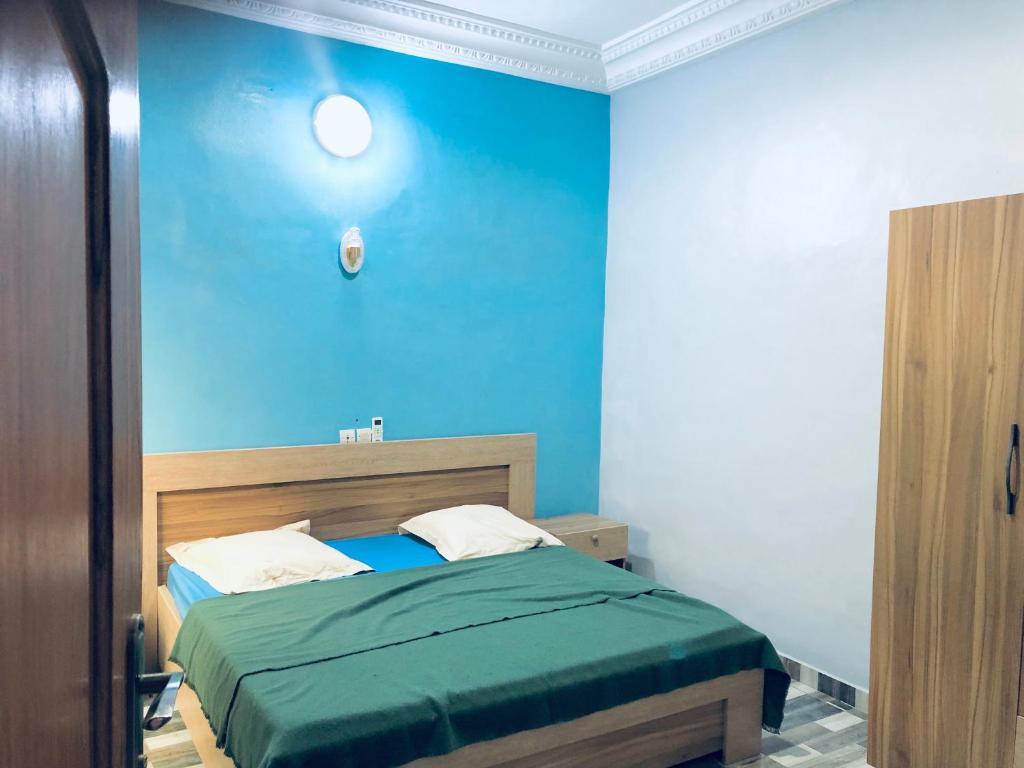 1 dormitorio con 1 cama con pared azul en Superbe maison dans un quartier calme - Bénin, en Ekpé