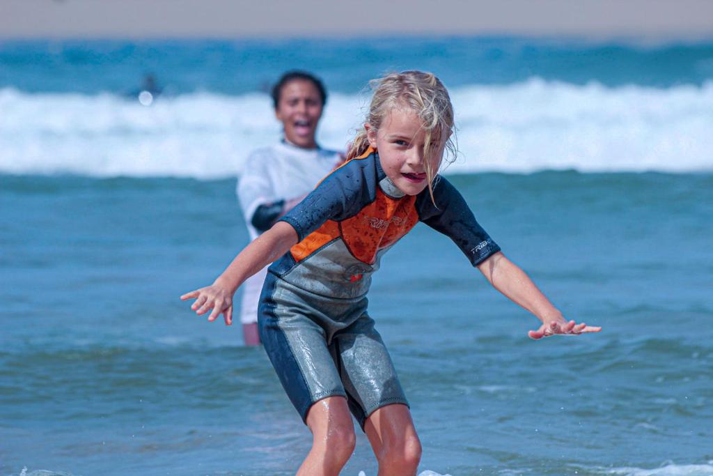 un niño pequeño jugando en el agua en la playa en Onda Surf en Taghazout