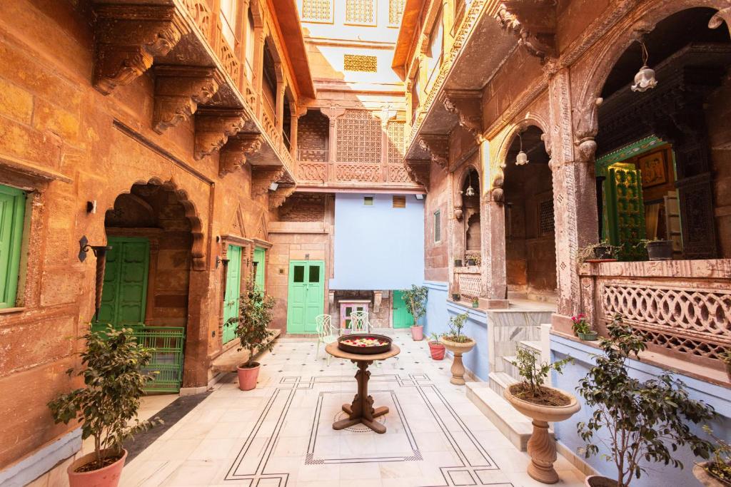 a courtyard in an old building with a table and potted plants at Amritara Manak Haveli, Jodhpur in Jodhpur