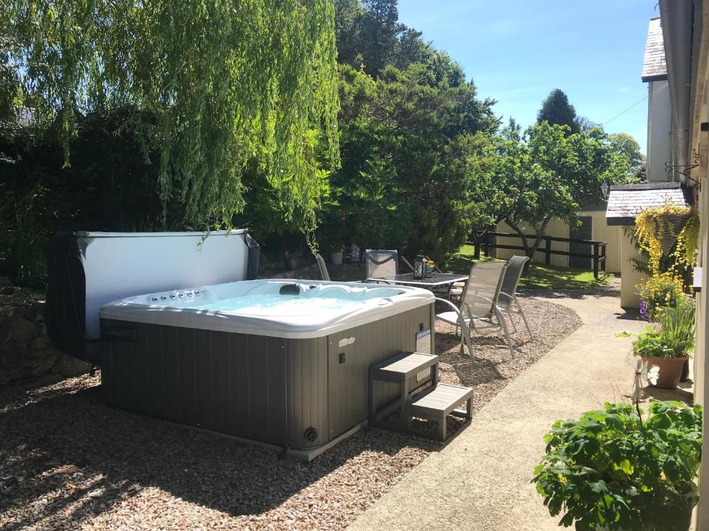 a hot tub in a yard with a table and chairs at the old rectory cottage in Pwllheli