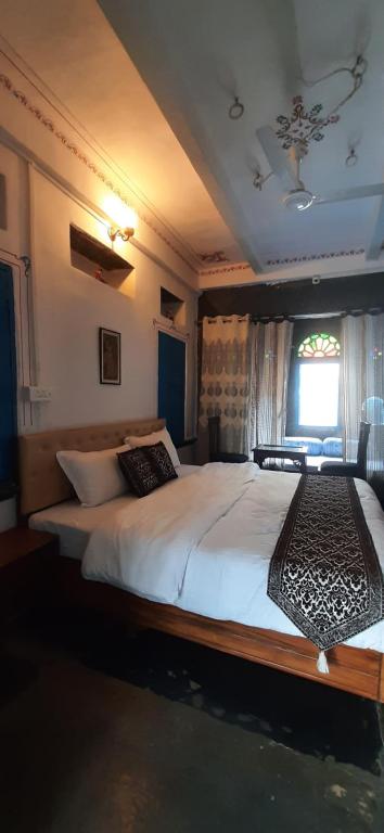 a bedroom with a large white bed with a window at Madan Mohan Villas (A Haritage Haveli Home Stay) in Udaipur