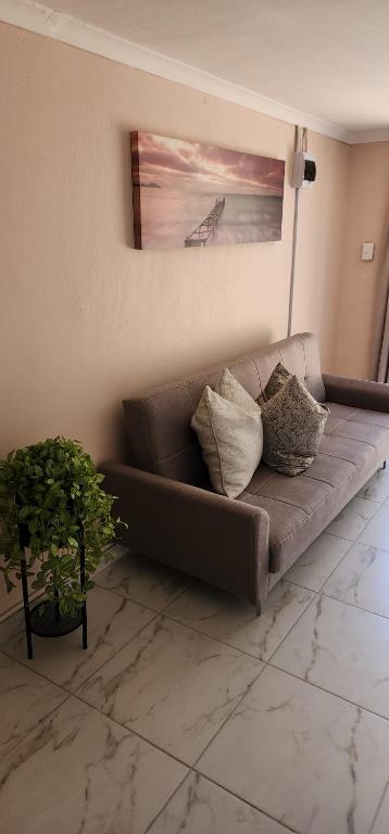 a brown couch with pillows in a living room at Cozy Batchelor Labiance in Cape Town