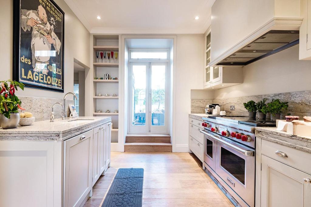 a kitchen with white cabinets and a sink and stove at The Notting Hill Townhouse in London