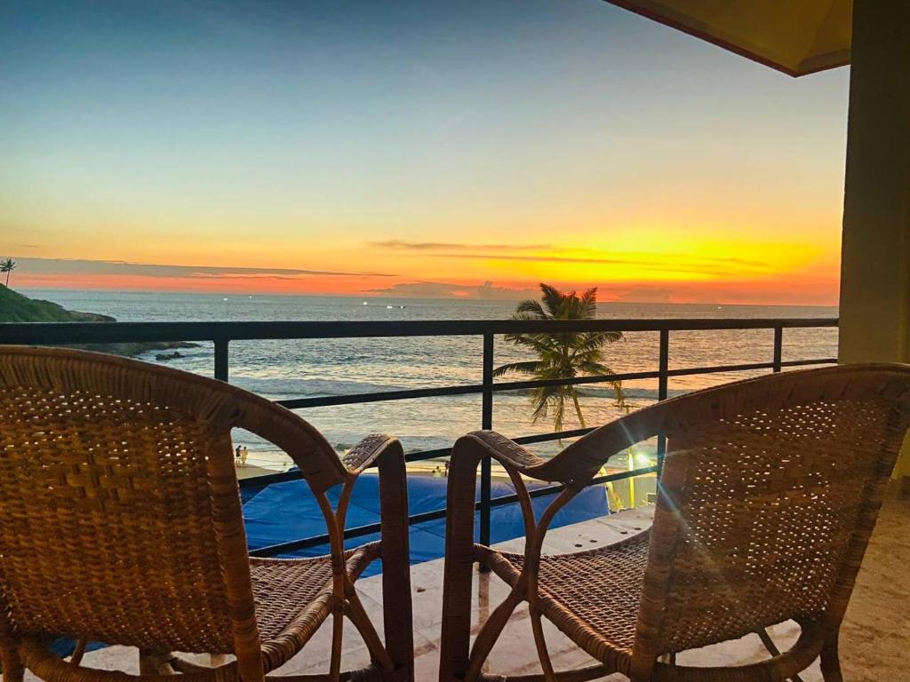 2 stoelen en een tafel op een balkon met een zonsondergang bij Karma Beach Resort in Kovalam
