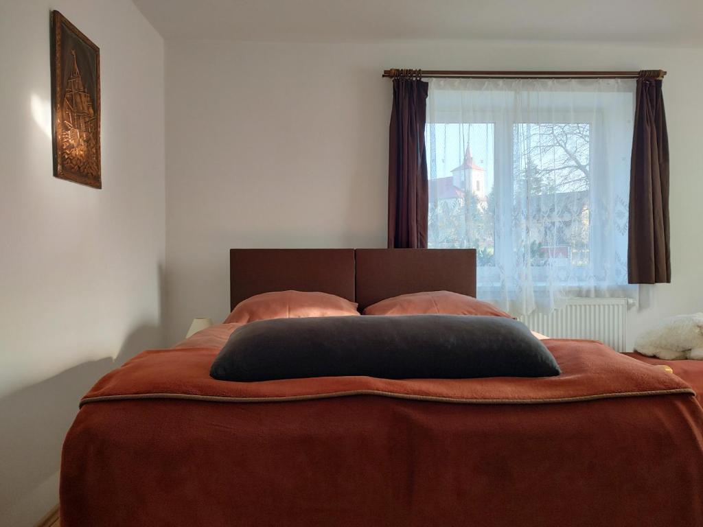 a bed with a brown blanket and a window at Apartmán Bystré in Bystré