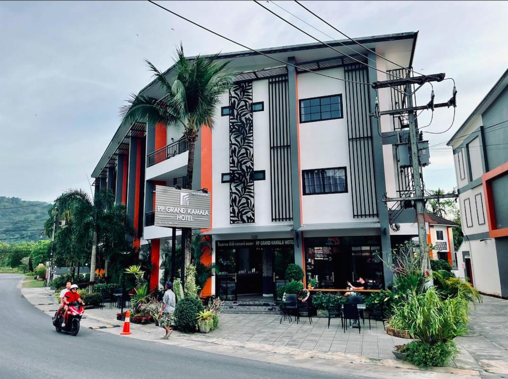 a person riding a motorcycle in front of a building at PP GRAND KAMALA HOTEL-SHA Extra Plus in Kamala Beach