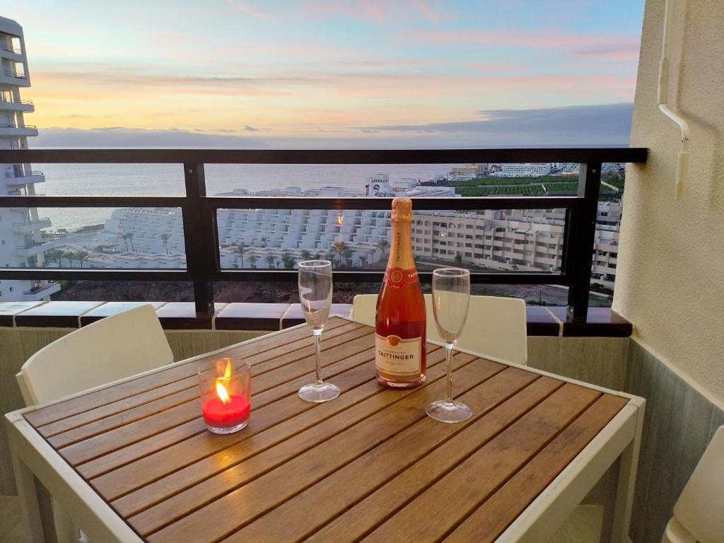 a bottle of wine and two glasses on a table with a candle at Relax And Sunset in Paraiso Adeje in Adeje