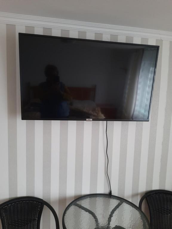 a tv hanging on a wall with a table and two chairs at Noclegi Studio Masażu in Włodawa