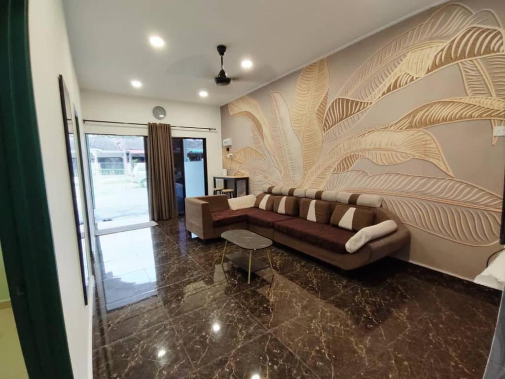 ein Wohnzimmer mit einem Sofa und einer Wand mit einem Wandbild in der Unterkunft JC HOMESTAY PORT DICKSON in Port Dickson