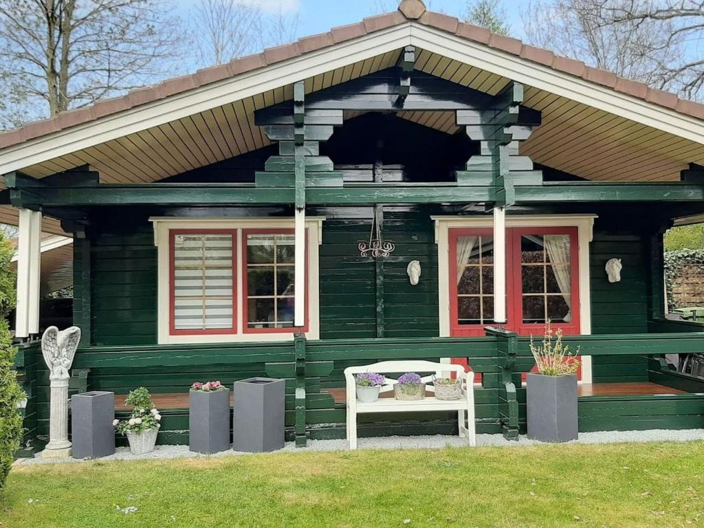 una casa verde con un banco blanco en el césped en Beautiful holiday home in Hulshorst with garden, en Hulshorst