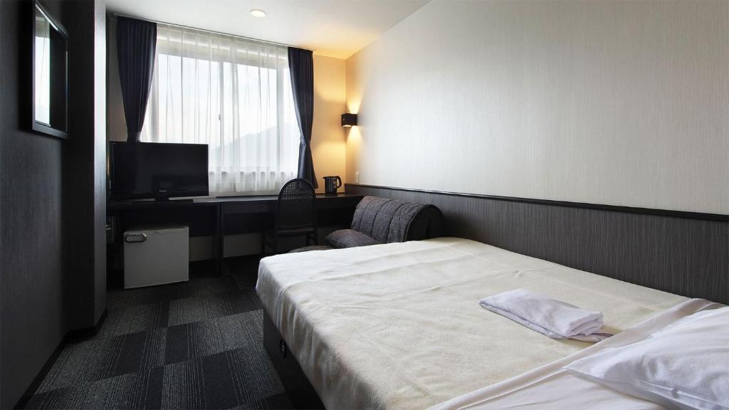 尾鷲市にあるHotel Vioraのベッドとテレビが備わるホテルルームです。