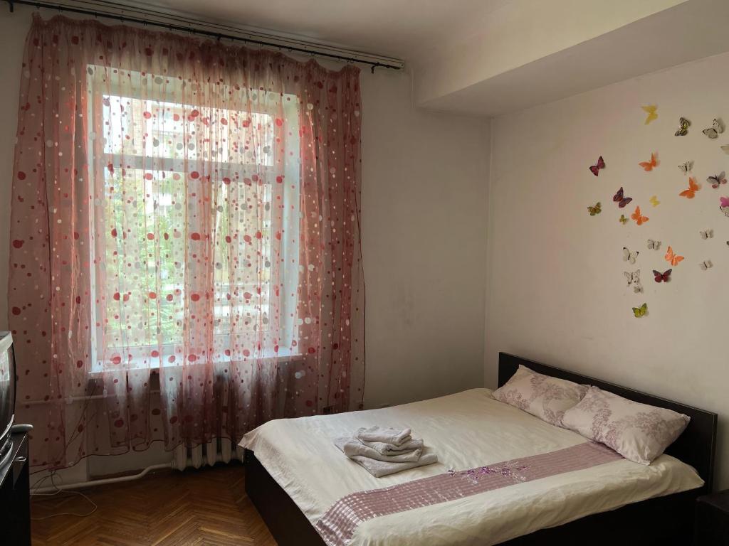 ein Schlafzimmer mit einem Bett und einem Fenster mit Schmetterlingen an der Wand in der Unterkunft 3х комнатная квартира возле парка in Riwne