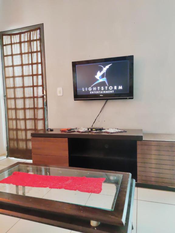 a living room with a tv and a table at Casa aconchegante in Campo Grande